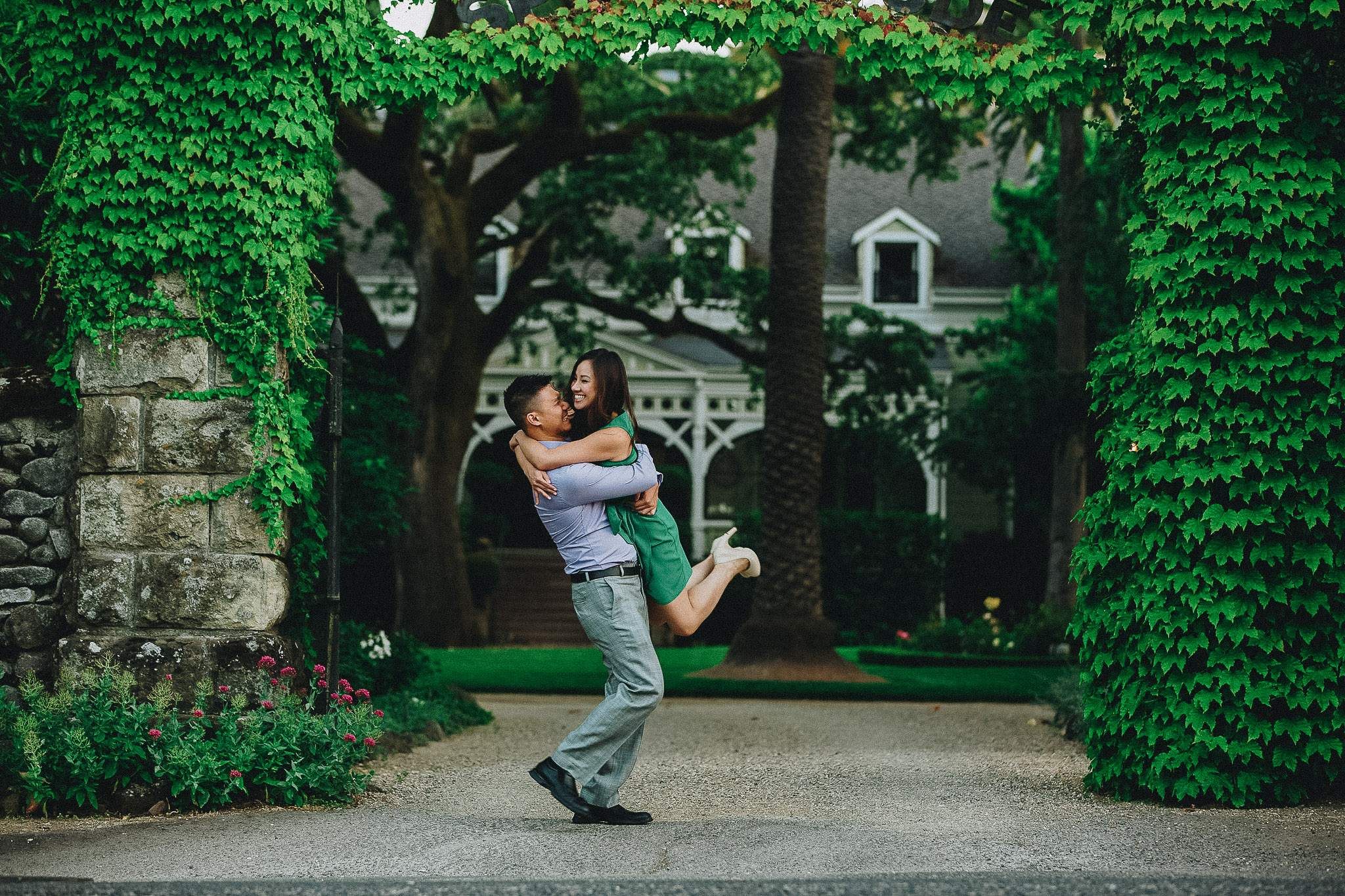 Wedding couple laughing together outside a green ivy covered entrance